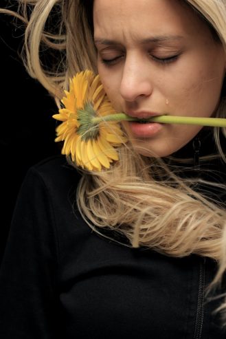 woman with sunflower in her mouth crying 