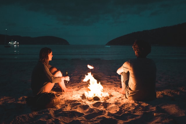 man and woman having bonfire in the beach 