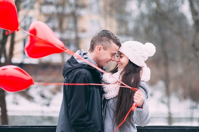 man and woman hugging with red ballons 