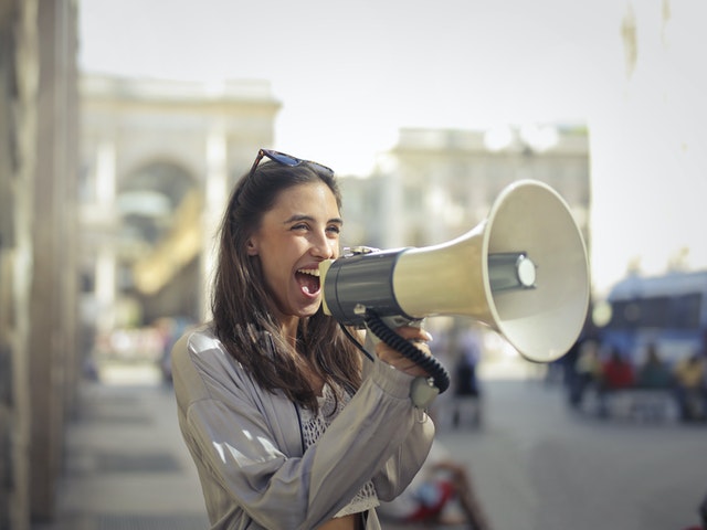 cheerful young woman screaming into a megaphone