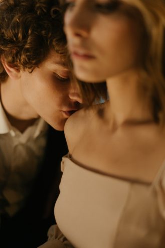 man kissing a woman's shoulder 