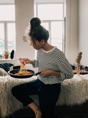 woman in black and white striped shirt eating food from pot