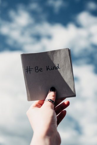 person holding a be kind note 