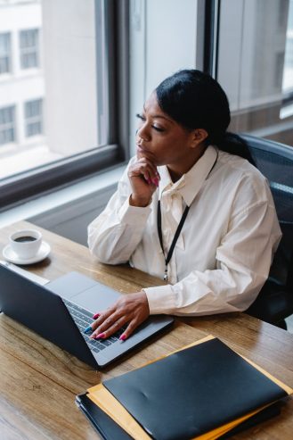 pensive woman working on laptop in modern workplace