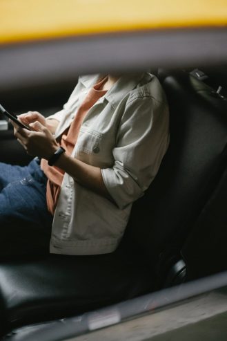  crop man sitting in taxi and browsing smartphone