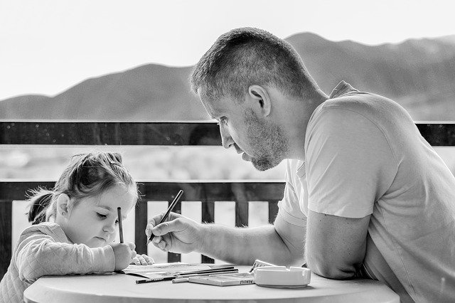 dad teaching his daughter how to write 