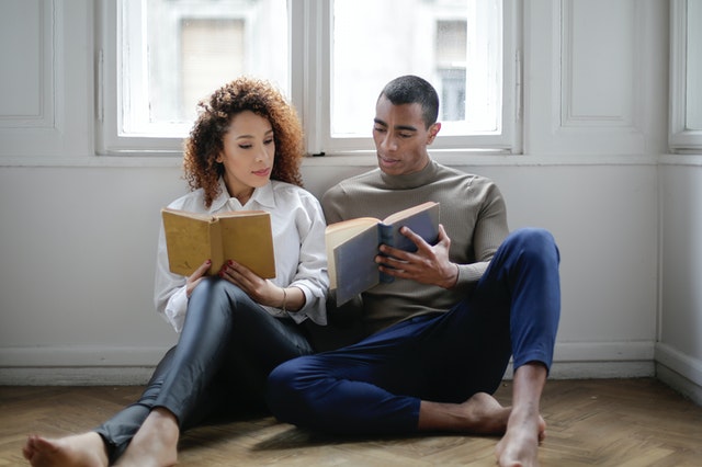 couple sitting on the floor reading book 