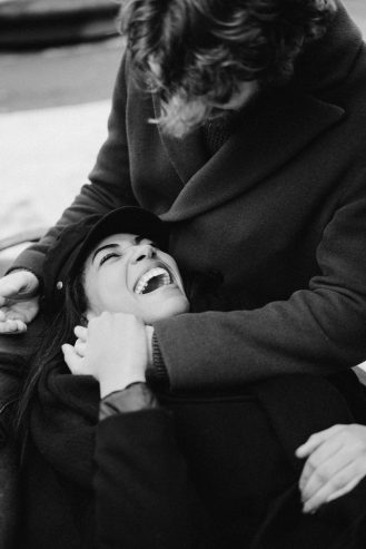 monochrome photo of woman lying on man's lap while laughing 