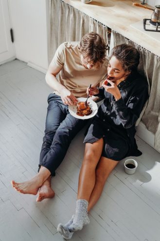 couple eating pancake on white wooden floor