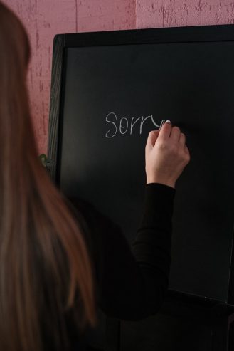 woman writing sorry on a board