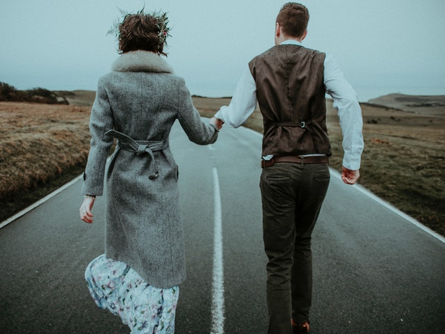 couple running on the road while holding hands
