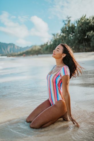 woman in a multicolored swimsuit sitting on the beach