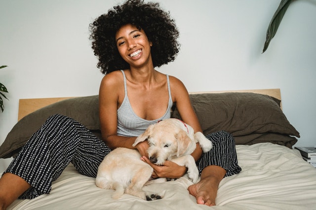 happy black woman with her dog resting at home 