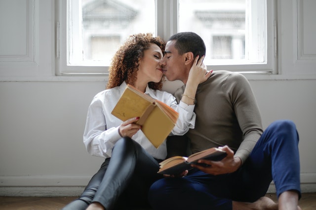 couple kissing while holding books